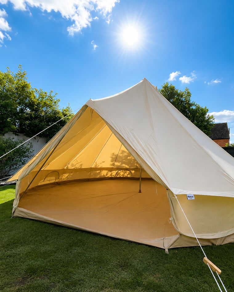 The bell tent pitched in a back garden in bright sunshine, guy ropes pegged out, doors open